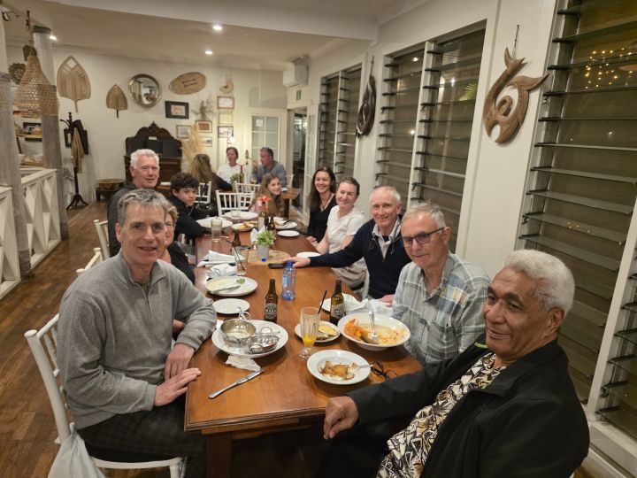 About ten people seated around a long dining table in a restaurant, smiling at the camera