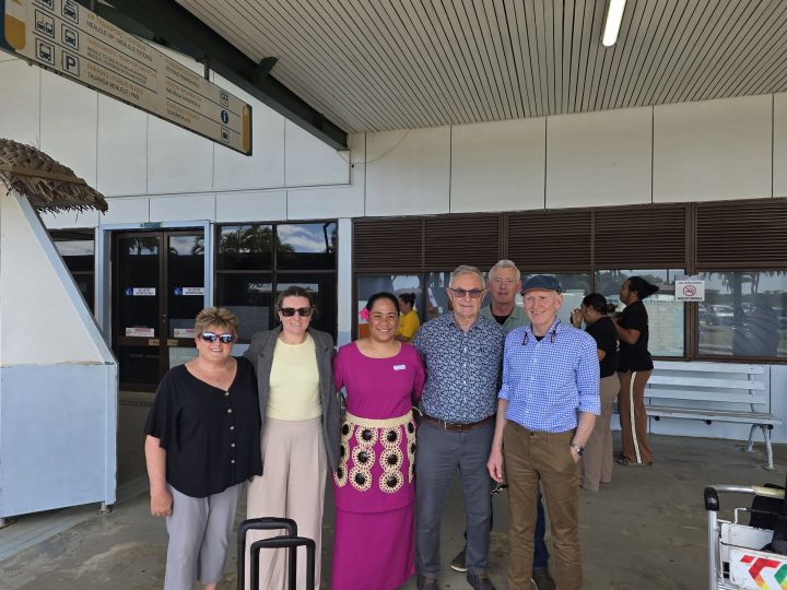 The visiting New Zealand surgical team standing with a Tongan representative outside the airport terminal in Tonga